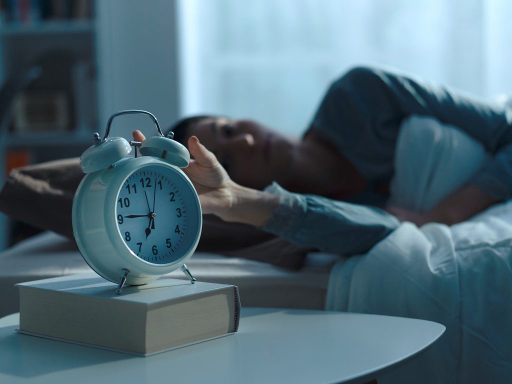 Woman waking up in the morning and alarm clock